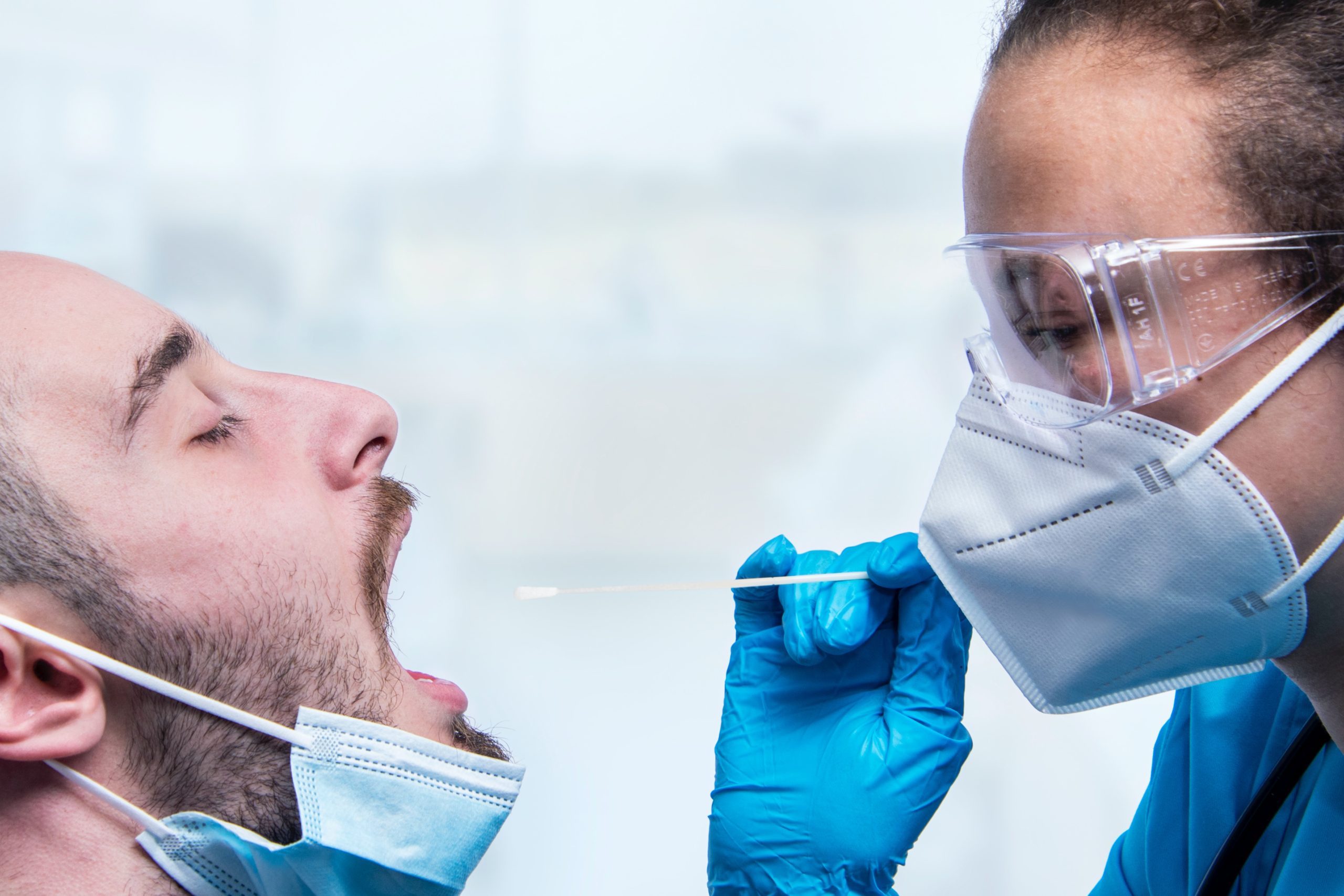 Female doctor with facemask swabbing patient's throat